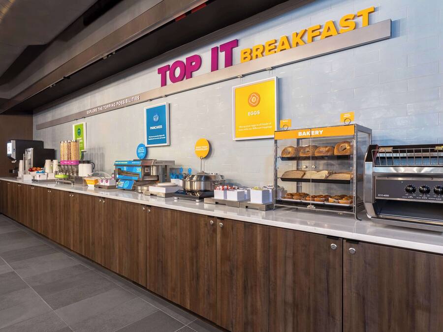 Een ontbijtstation met een bord waarop 'TOP IT BREAKFAST' staat, en diverse etenswaren.