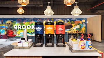Ein Kaffeeangebot mit vier Spendern, beschriftet mit 'Brook Lavazza Decaf', 'Brook Lavazza Regular', 'Brook Lavazza Heißwasser' und 'Coffee Mate'.