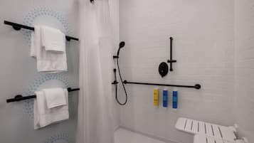 A modern bathroom with white tiled walls, a shower with a black handle, and a white toilet.