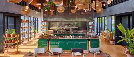 A modern kitchen with green cabinets, a central island, and hanging planters.