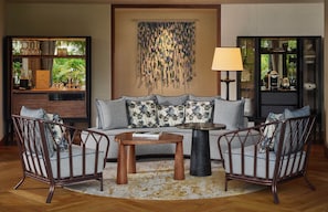 A living room with a sofa, two armchairs, a coffee table, a lamp, and a decorative wall piece. - Waldorf Astoria Seychelles Platte Island (Platte Island)