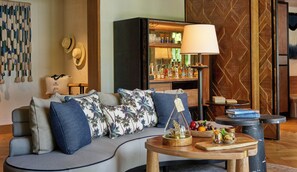 A cozy living area with a sofa, a coffee table, and a bookshelf. - Waldorf Astoria Seychelles Platte Island (Platte Island)