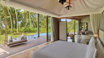Quarto espaçoso com uma cama grande, um deck de madeira e vista para um verde exuberante.