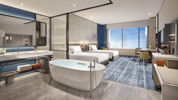 Et moderne hotelværelse med et stort badekar, to senge, et siddeområde og udsigt over byen.