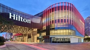 Et moderne hotel med et tydeligt 'Hilton' skilt, store glasfacade og en buet front.