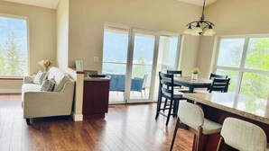 A spacious kitchen with a dining area, large windows, and a sliding glass door leading to a balcony.
