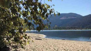 A beach with a sandy shore, trees, and a lake in the background.