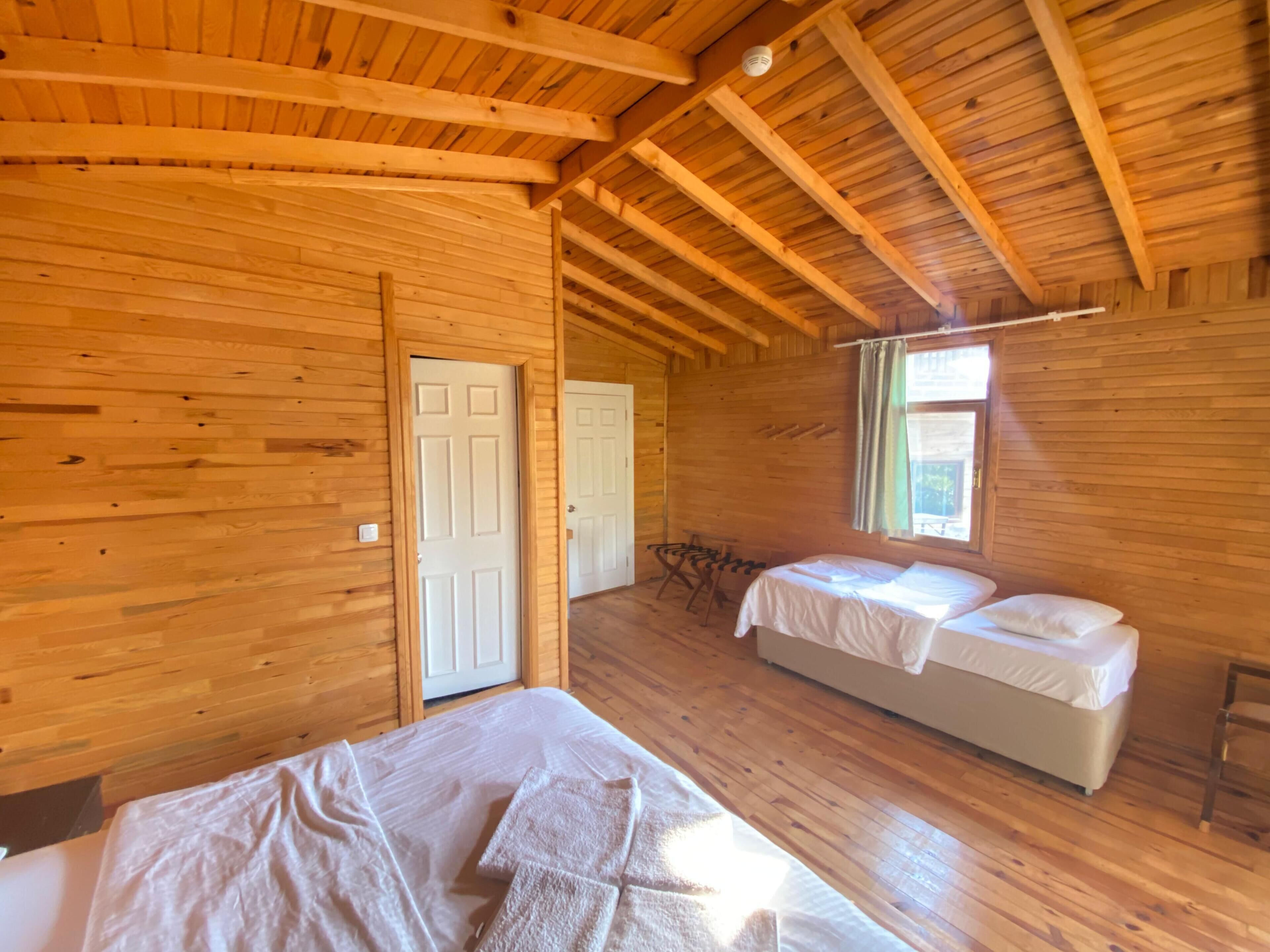 Una habitación tipo cabaña de madera con dos camas, una puerta y una ventana.