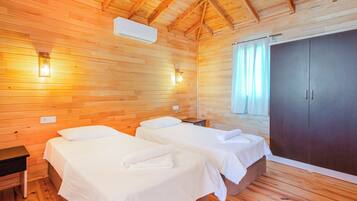 Una habitación de cabaña de madera con dos camas, un armario y una mesita de noche.