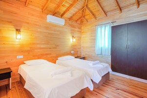 Una habitación de cabaña de madera con dos camas, un armario y una mesita de noche.