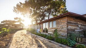 A stone building with a wooden exterior, a stone pathway, and surrounding greenery. - Kadir's Eco Life (Kumluca)