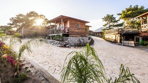 A rustic wooden building with a balcony, surrounded by cobblestone paths and greenery. - Kadir's Eco Life (Kumluca)