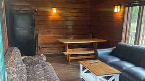 Ein Holzblockbau-Innenraum mit einer Couch, einem Holztisch und einem schwarzen Ledersofa.