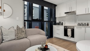 A modern kitchen with white cabinets, a built-in oven, and a large window. - Designer Living at The Tokyo, No Loadshedding (Cape Town)