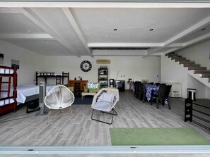 A spacious living area with a dining table, two beds, a kitchen area, and a staircase.