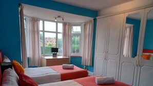 Habitación de hotel con dos camas, un escritorio y un armario.