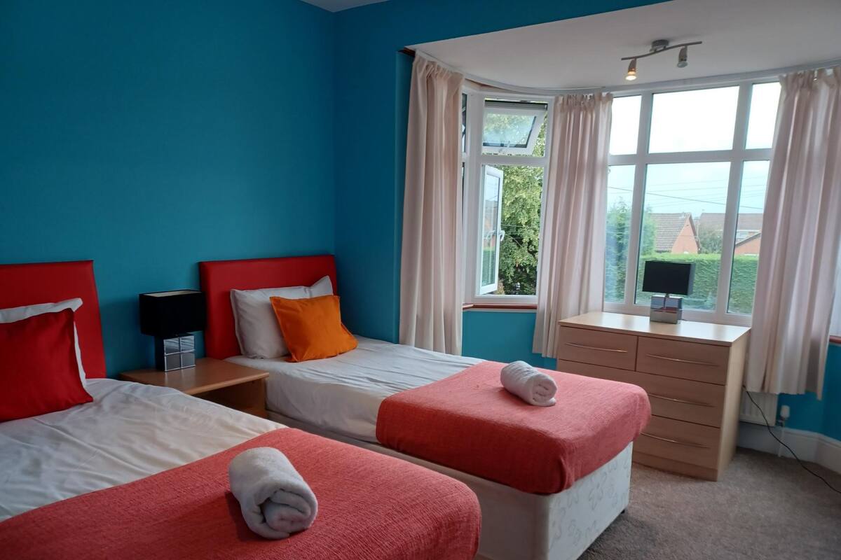 Habitación de hotel con dos camas, un escritorio y una ventana con cortinas.