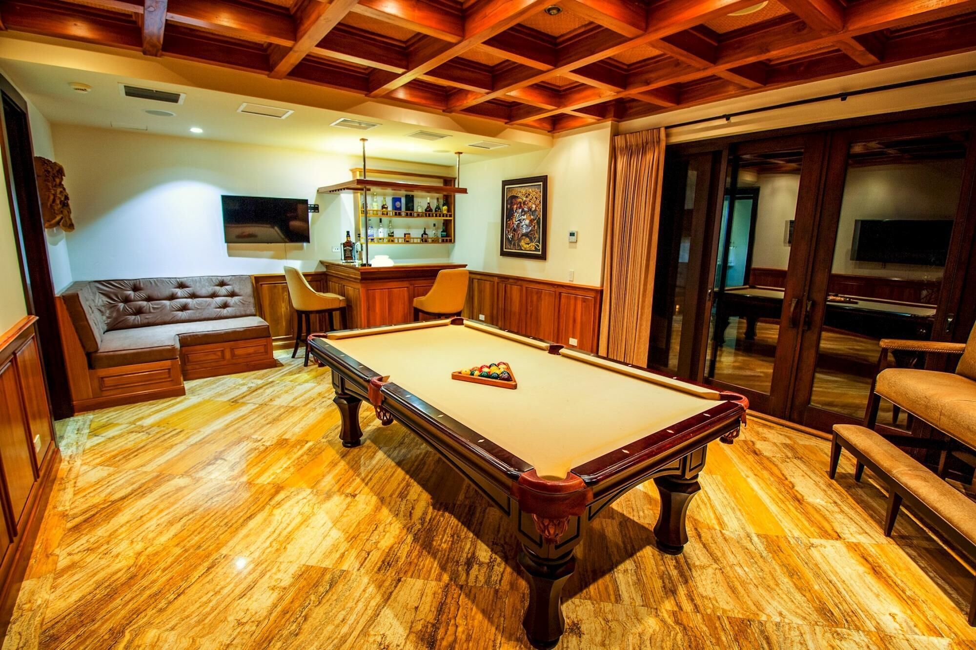 Une table de billard dans une pièce au plancher en bois et au plafond haut.