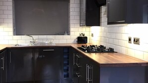 A modern kitchen with black cabinets, a wooden countertop, and a built-in stove. - HU1 Stylish cosy central apartment  H3 (Hull)