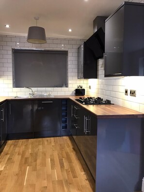 A modern kitchen with black cabinets, a wooden countertop, and a built-in stove. - HU1 Stylish cosy central apartment  H3 (Hull)