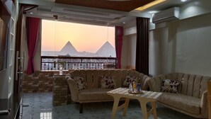 A living room with a sofa, a small table, and a view of pyramids. - Pyramids View apartment (Giza Governorate)
