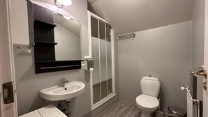 Een badkamer met een wit wastafel, toilet, een douchecabine van glas en een spiegel met een zwarte lijst.