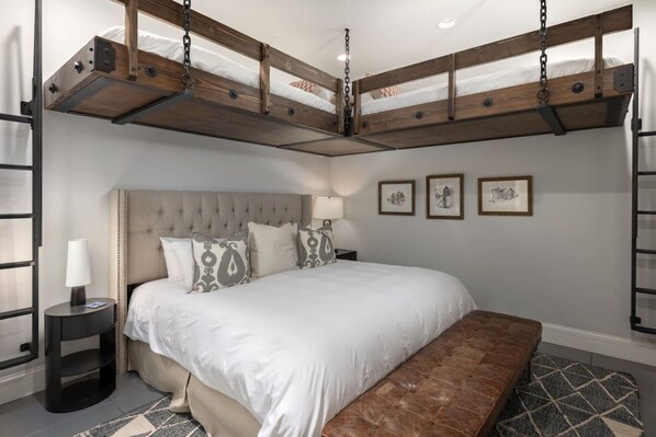 A bedroom with a large bed, a headboard, bedside tables, and a bench.