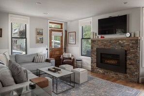 A living room with a fireplace, a sofa, a coffee table, and a television mounted on the wall.