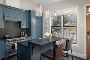 Una cucina con mobili blu, un'isola centrale, un piano cottura e luci a sospensione.