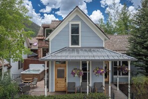 A two-story house with a covered porch, a hot tub, and outdoor seating.