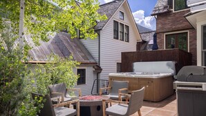 A patio area with a hot tub, seating, and a grill.
