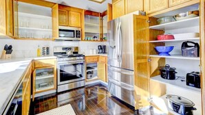 A modern kitchen with wooden cabinets, stainless steel appliances, and open shelving.
