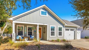 A single-story house with a front porch, a garage, and a small garden area. - Sands About Right
 (Oak Island)