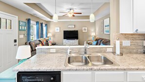 A modern kitchen with a double sink, a dishwasher, and a ceiling fan. - Sands About Right
 (Oak Island)