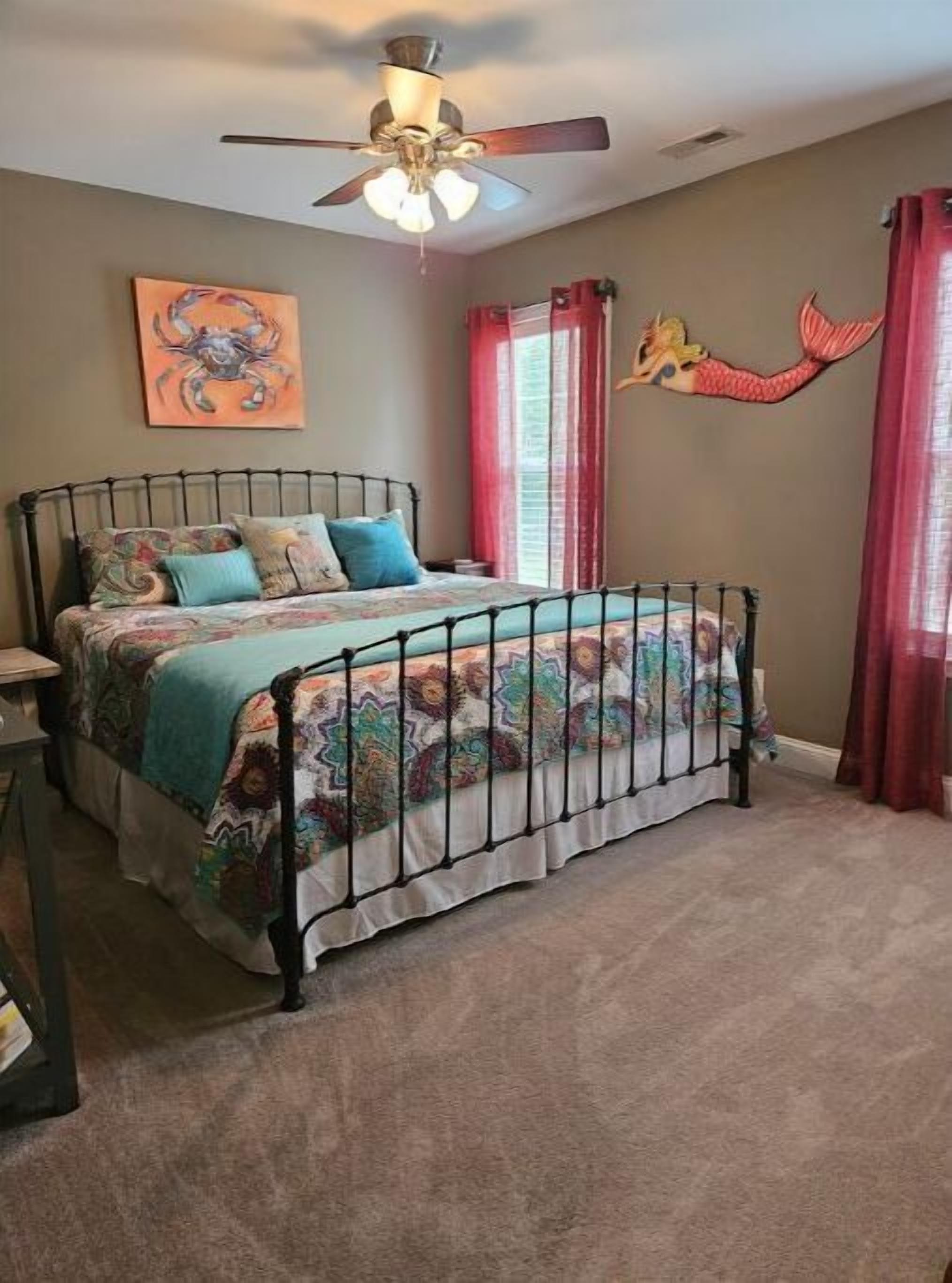 Una camera da letto con un letto, una ventola a soffitto, un quadro e una decorazione a tema sirena.