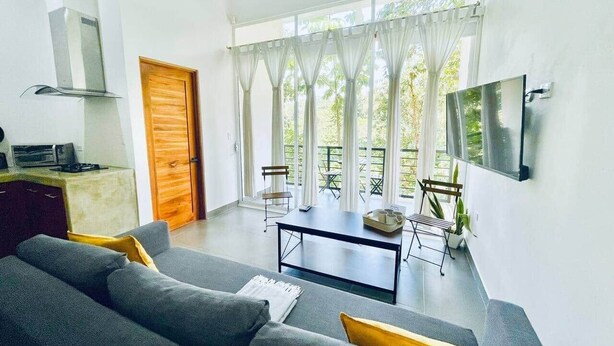 Ein modernes Wohnzimmer mit einer Couch, einem Tisch und einem an der Wand montierten Fernseher.