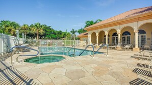 A pool area with a clear pool, lounge chairs, and a building with arches. - Fort Myers Condo: Community Pool + Fitness Center (Fort Myers)