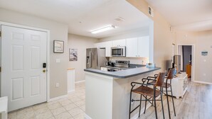 A spacious kitchen with a central island, bar stools, and modern appliances. - Fort Myers Condo: Community Pool + Fitness Center (Fort Myers)