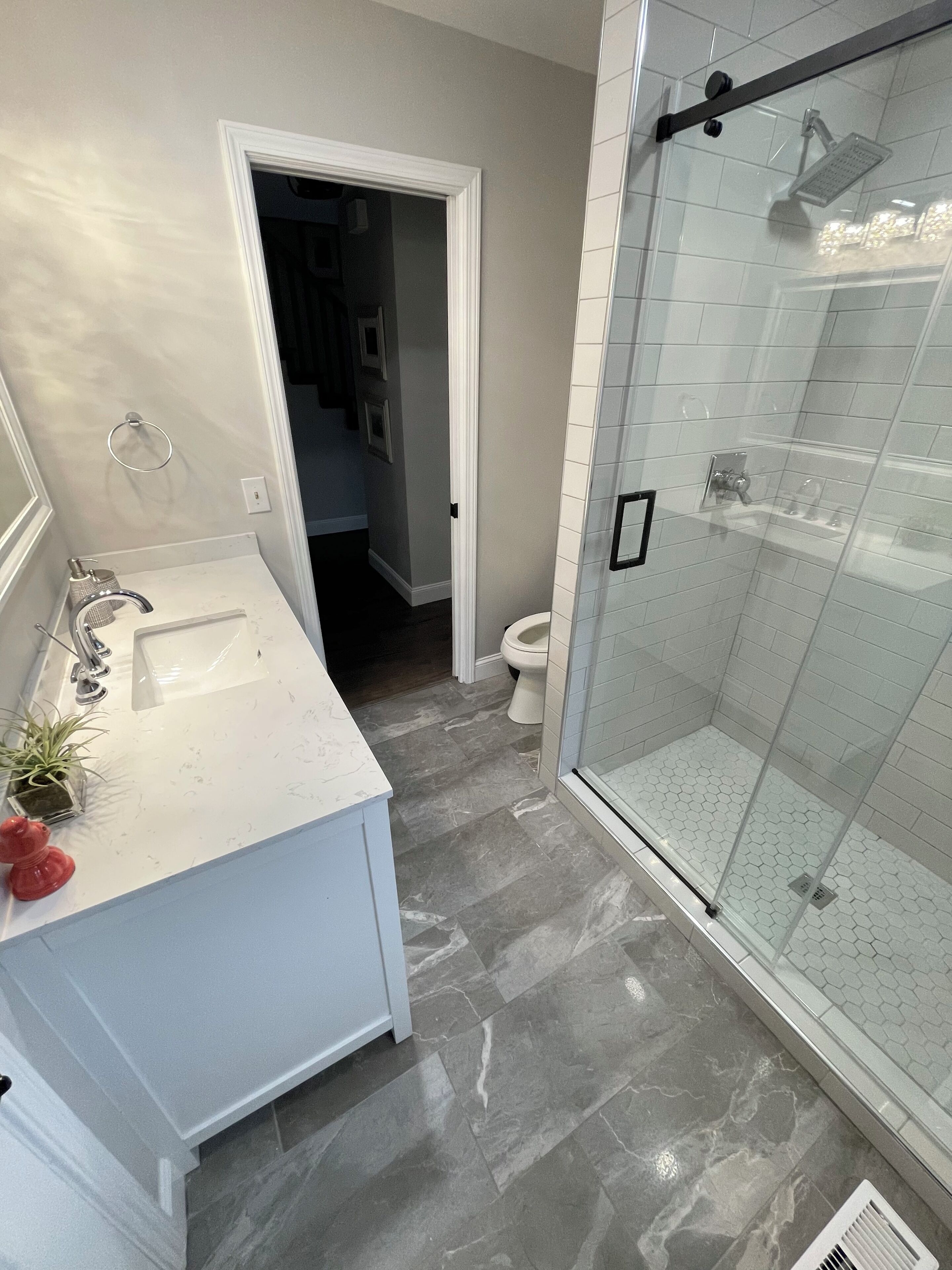 A bathroom with a white vanity, a glass shower enclosure, and a tiled floor.