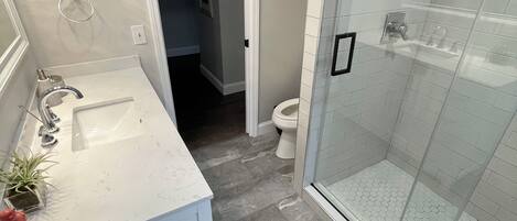A bathroom with a white vanity, a glass shower enclosure, and a tiled floor.