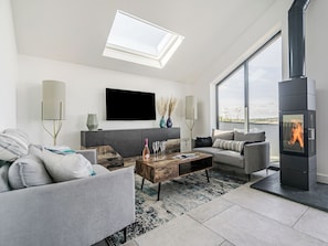 A modern living room with a fireplace, a flat-screen TV, and a large window.