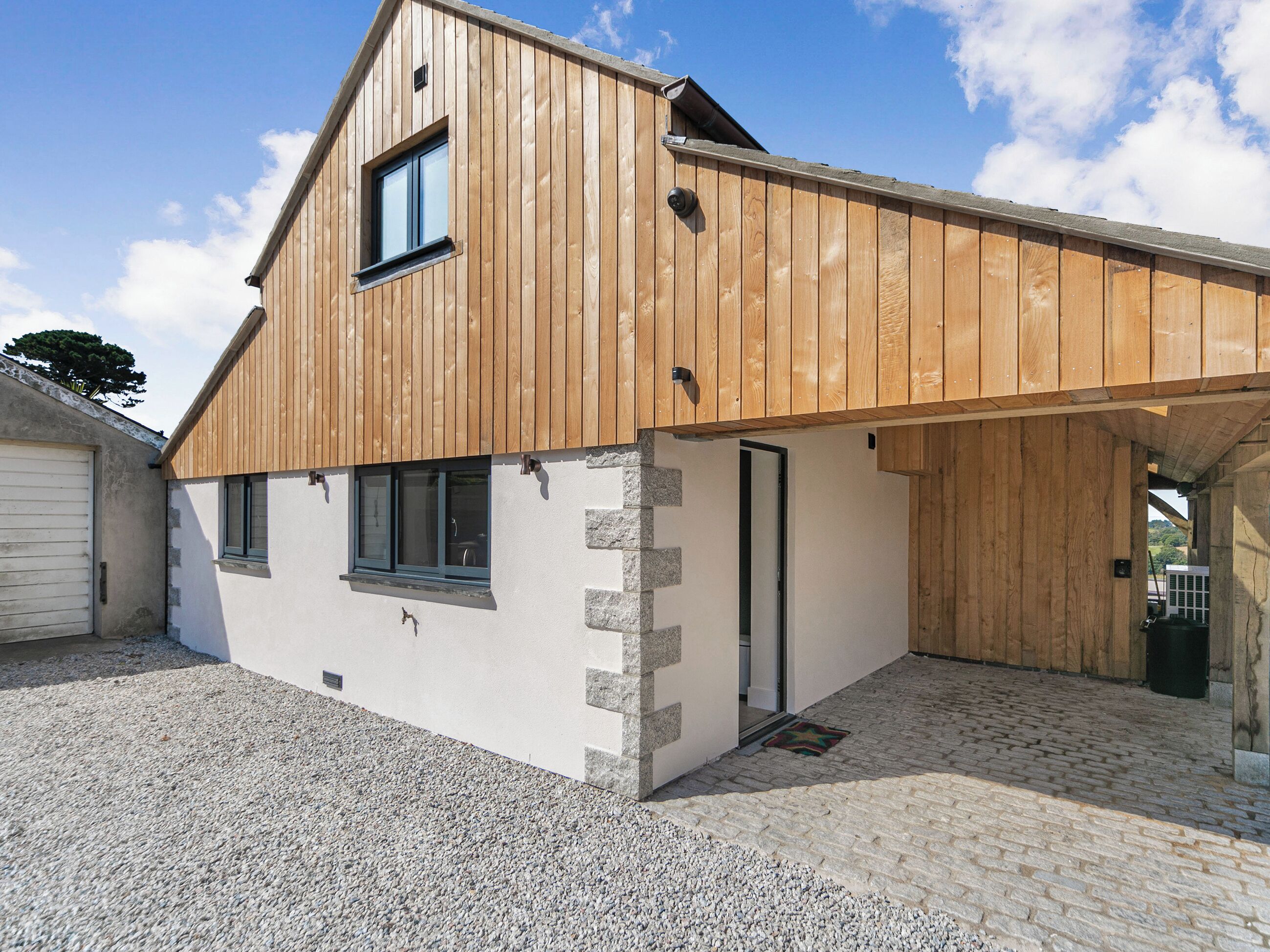 A modern building with a sloped roof, a garage, and a gravel driveway.