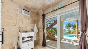 Une salle de bain équipée d’une douche, d’un lavabo, d’un porte-serviettes et d’un seau.