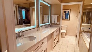 A modern bathroom with two sinks, a toilet, and a bathtub. - Four Bed Room Presidential Suite (Las Vegas)