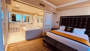 A hotel room with a large bed, a separate bathroom with a bathtub, and a view of the city. - Four Bed Room Presidential Suite (Las Vegas)