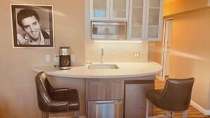 A compact kitchen with a sink, a coffee maker, and two bar stools. - Four Bed Room Presidential Suite (Las Vegas)