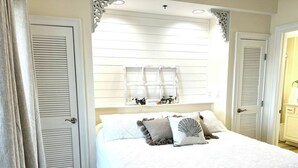 Une chambre à coucher avec un grand lit, des rideaux blancs et une fenêtre avec des volets.
