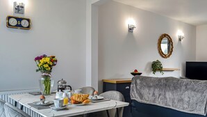Een moderne woonkamer met een bank, een eettafel met stoelen, een koffiezetapparaat en een bloevas.