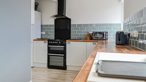 Een moderne keuken met witte kasten, een zwarte kookplaat, een magnetron en een broodrooster.
