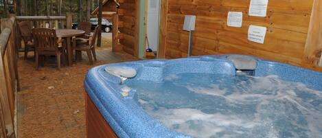 Eine Holzhütte mit Whirlpool, einer Holzterrasse und einem Tisch mit Stühlen.